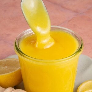 a metal spoon scooping vegan lemon curd out of a glass jar