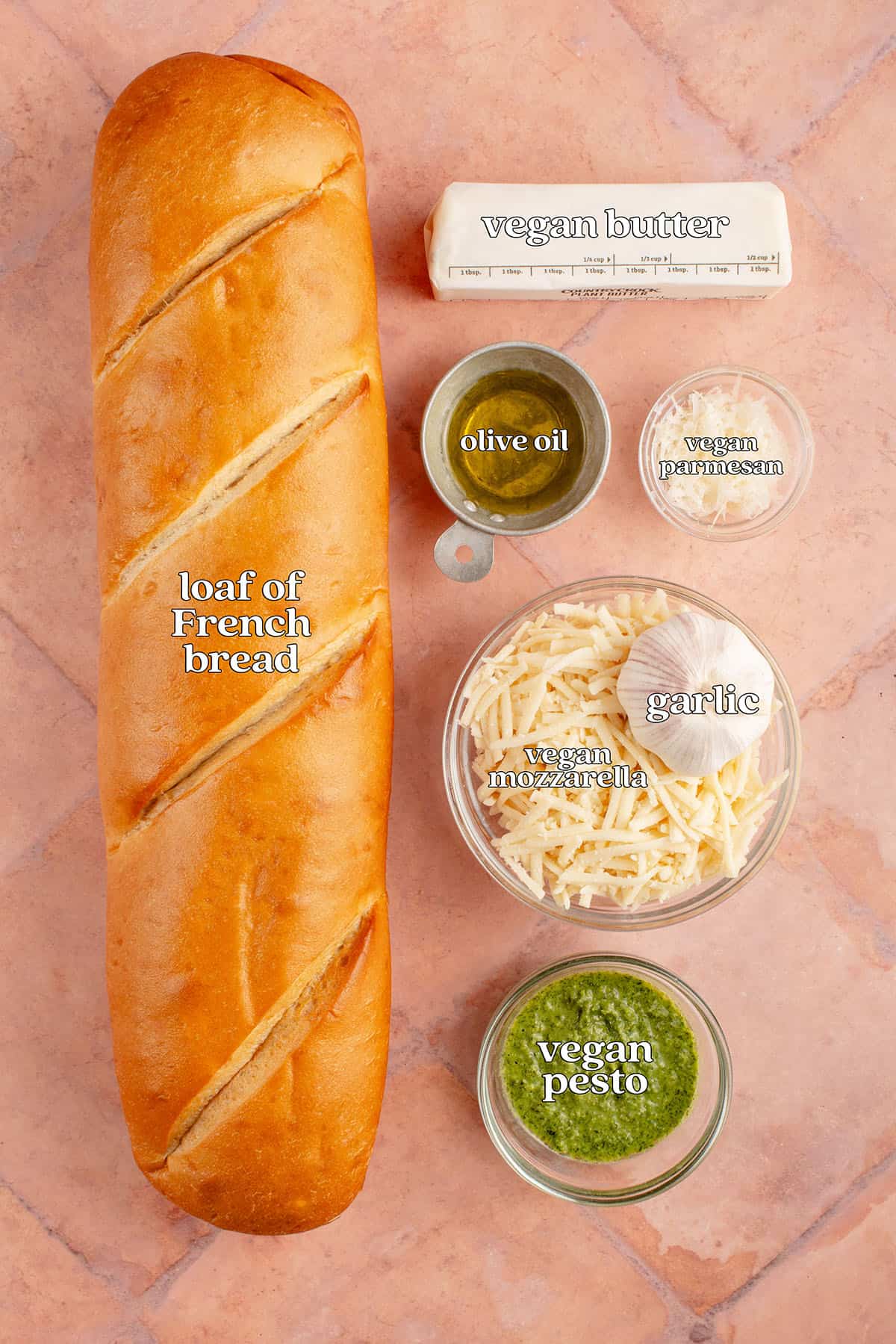 loaf of French bread, vegan butter, olive oil, vegan parmesan, garlic, vegan mozzarella, vegan pesto