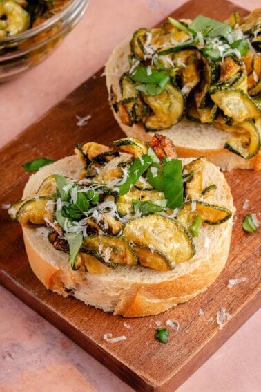 fried zucchini on sliced bread topped with vegan parmesan and sliced basil