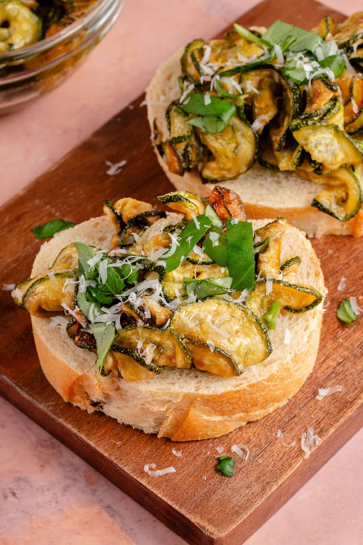 fried zucchini on sliced bread topped with vegan parmesan and sliced basil