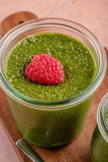 Close up of a glass of matcha chia pudding with a raspberry on top