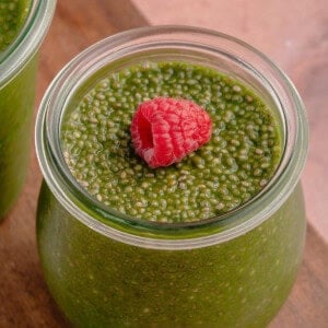 Close up of a glass of matcha chia pudding with a raspberry on top