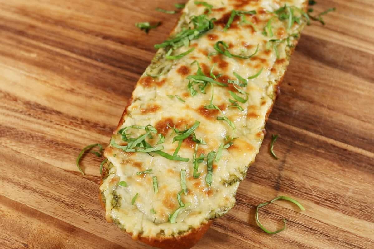 adding sliced basil on top garlic bread