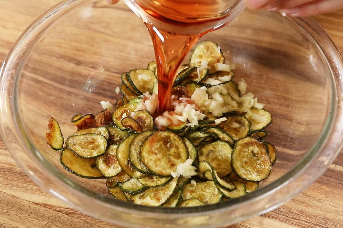 red wine vinegar being poured into the fried zucchini