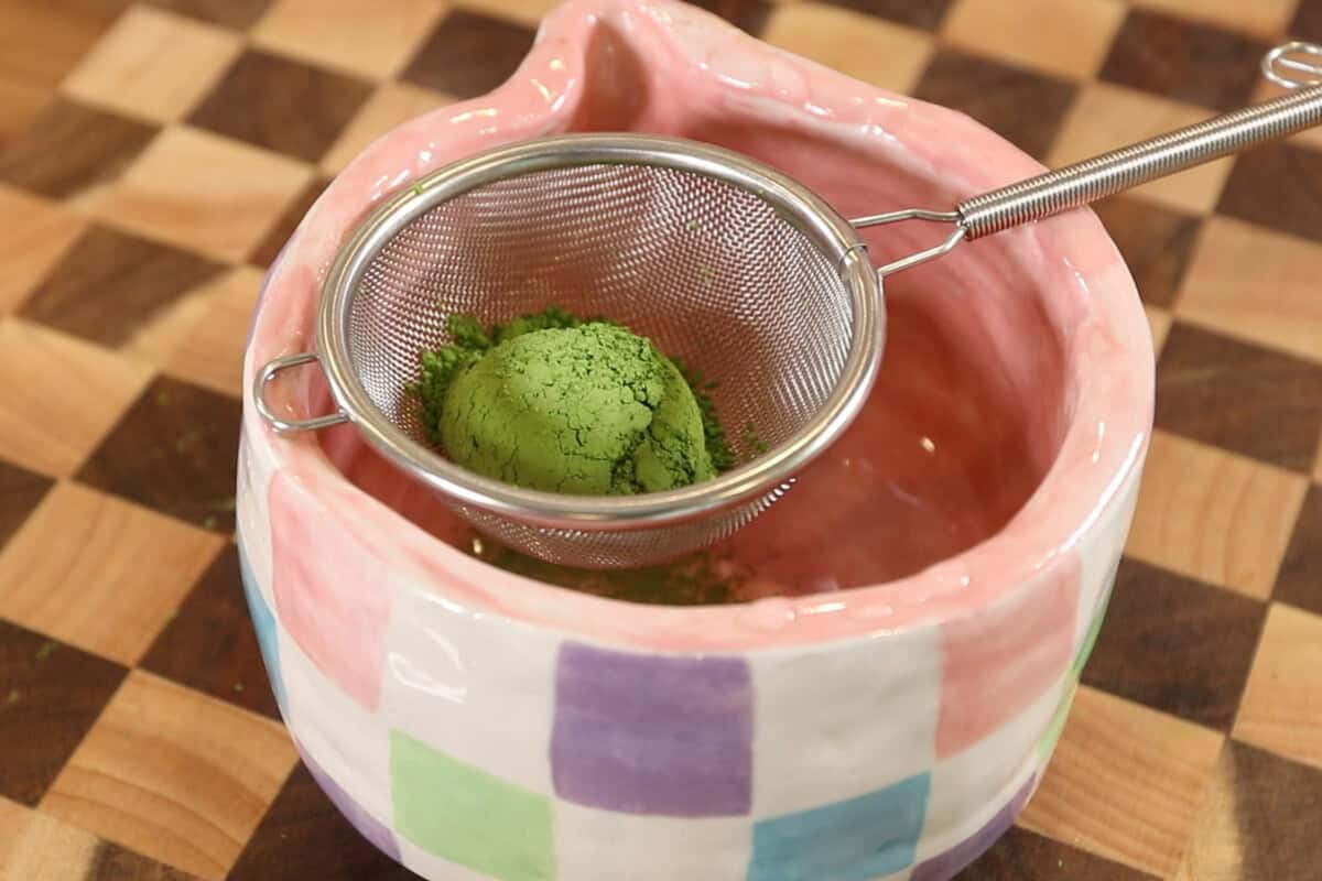 sifting matcha powder into a bowl