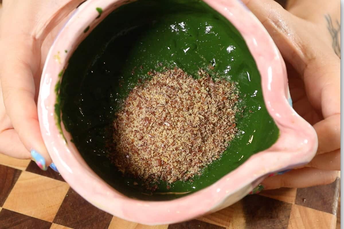 adding flaxseed meal to a pink bowl with matcha