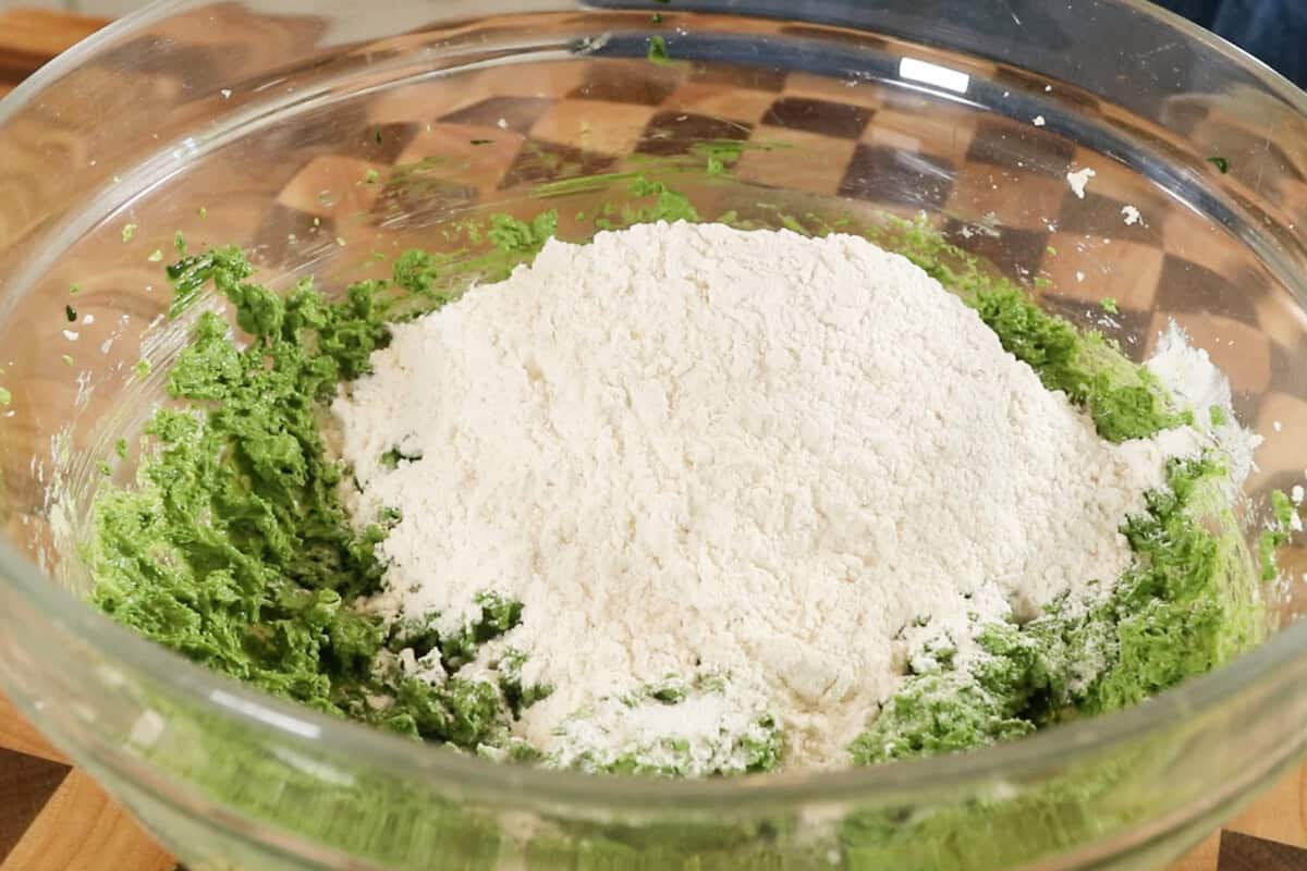 adding dry ingredient for Vegan Matcha Sugar Cookies in a large glass bowl