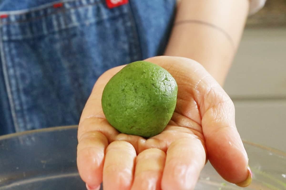 palm with a ball of vegan matcha sugar cookie dough