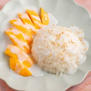 photo of mango sticky rice on a blue plate on a pink table