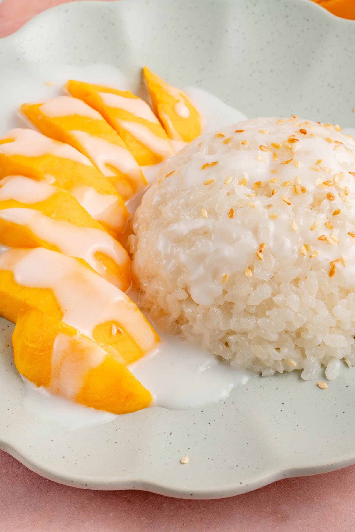 close up photo of mango sticky rice on a blue plate on a pink table