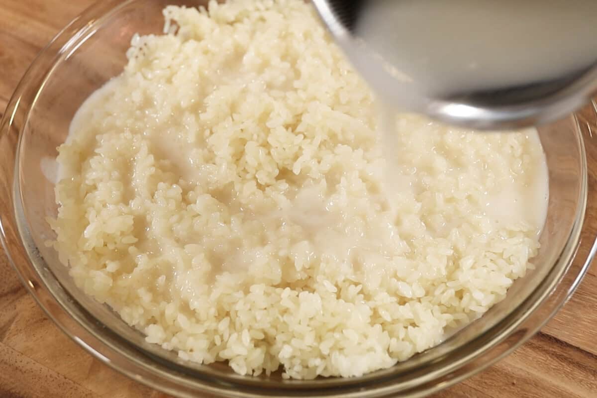 pouring coconut milk sauce over cooked glutinous rice for mango sticky rice recipe