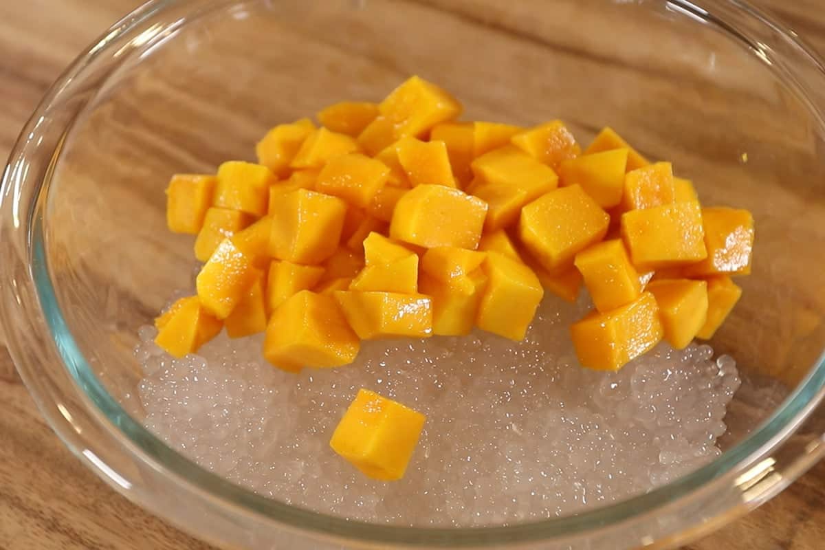 cooked tapioca pearls and chopped mango in large glass bowl for mango sago