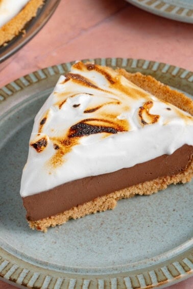 close up photo of a slice of S'mores Pie with toasted meringue topping on a blue plate