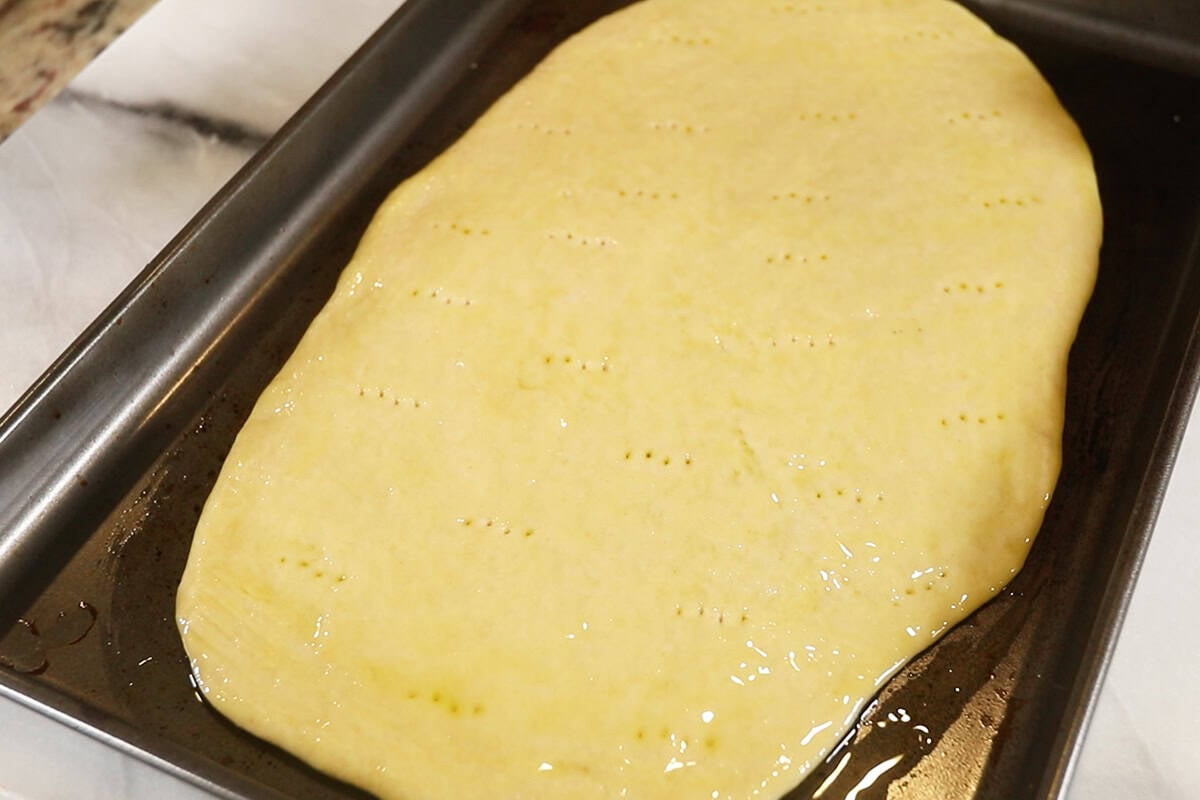 oiled plain Flatbread on dark baking sheet before baking