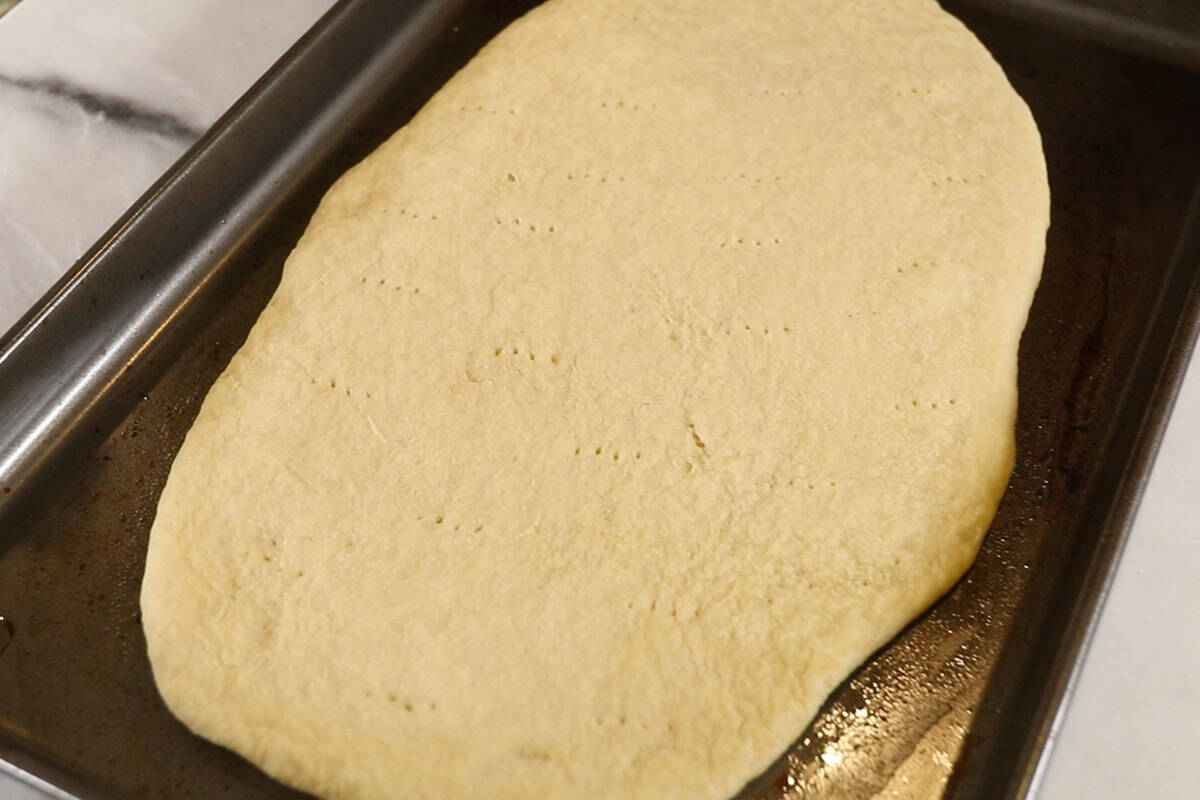parbaked plain Flatbread before toppings on dark baking sheet