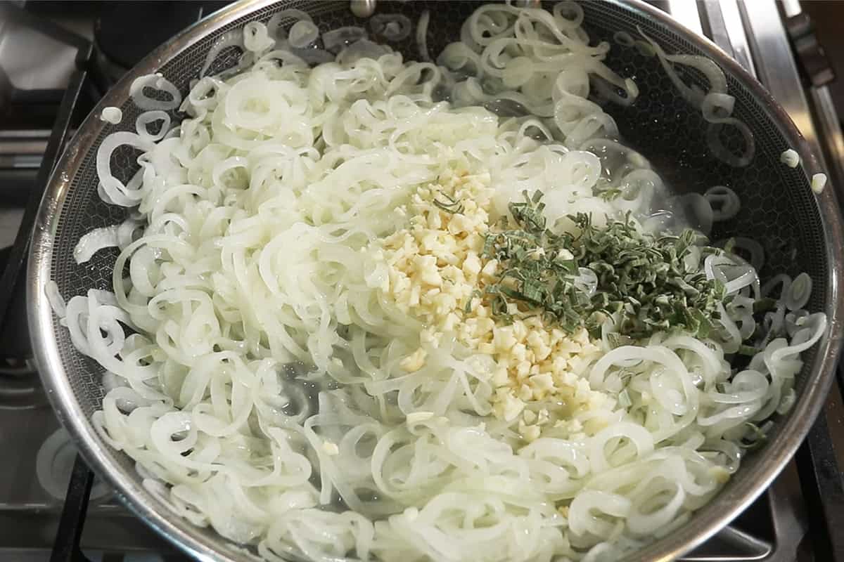 caramelizing onions with garlic and sage on large dark skillet
