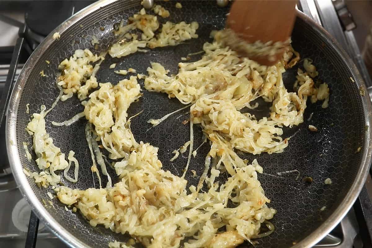 caramelizing onions with garlic and sage on large dark skillet