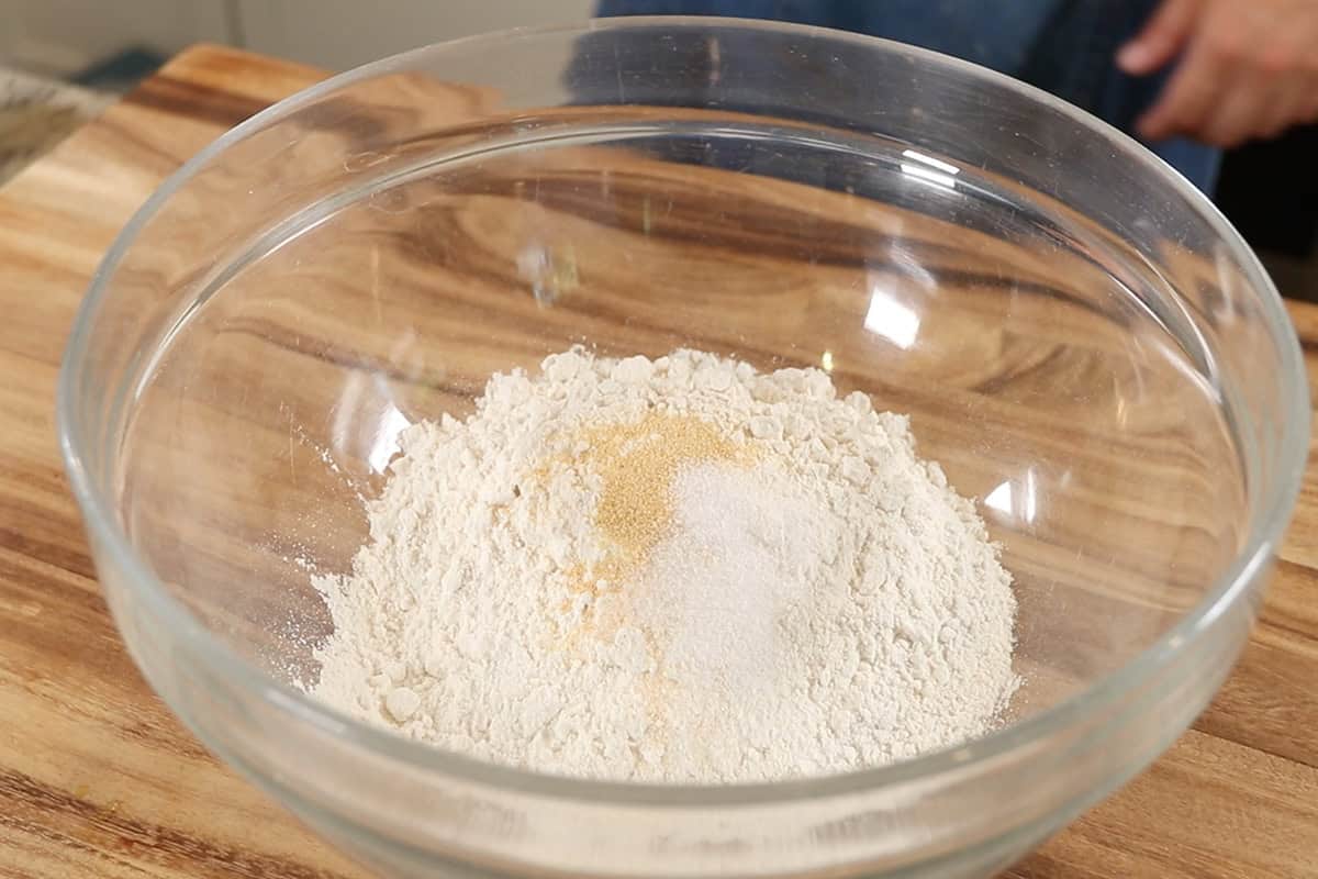 mixing ingredients for flatbread dough in large glass bowl