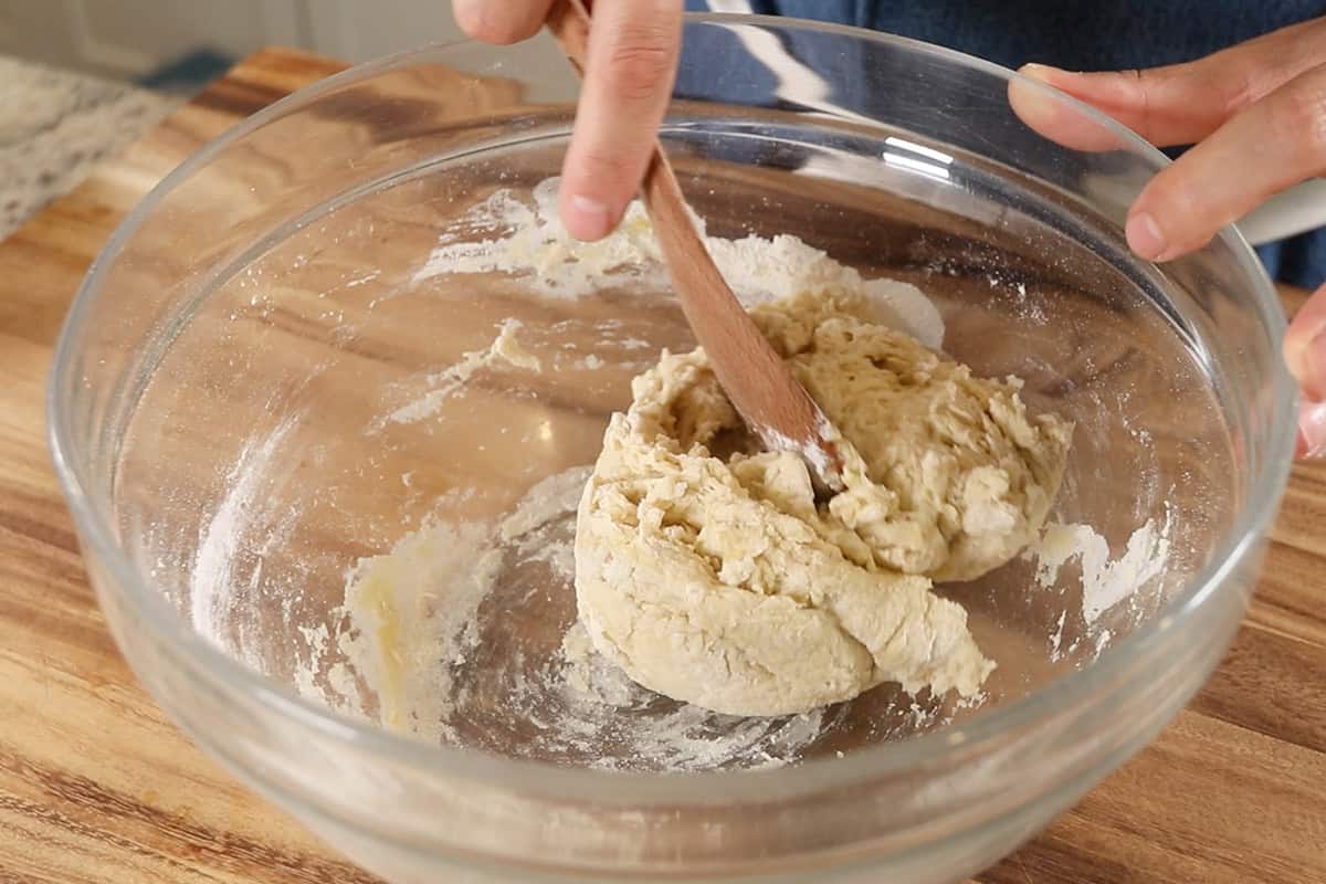 mixing ingredients for flatbread dough in large glass bowl