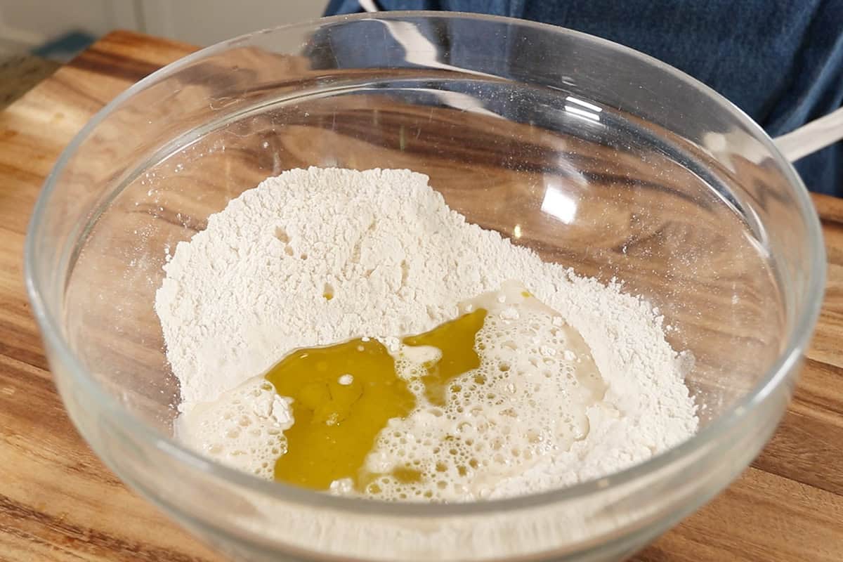 mixing ingredients for flatbread dough in large glass bowl