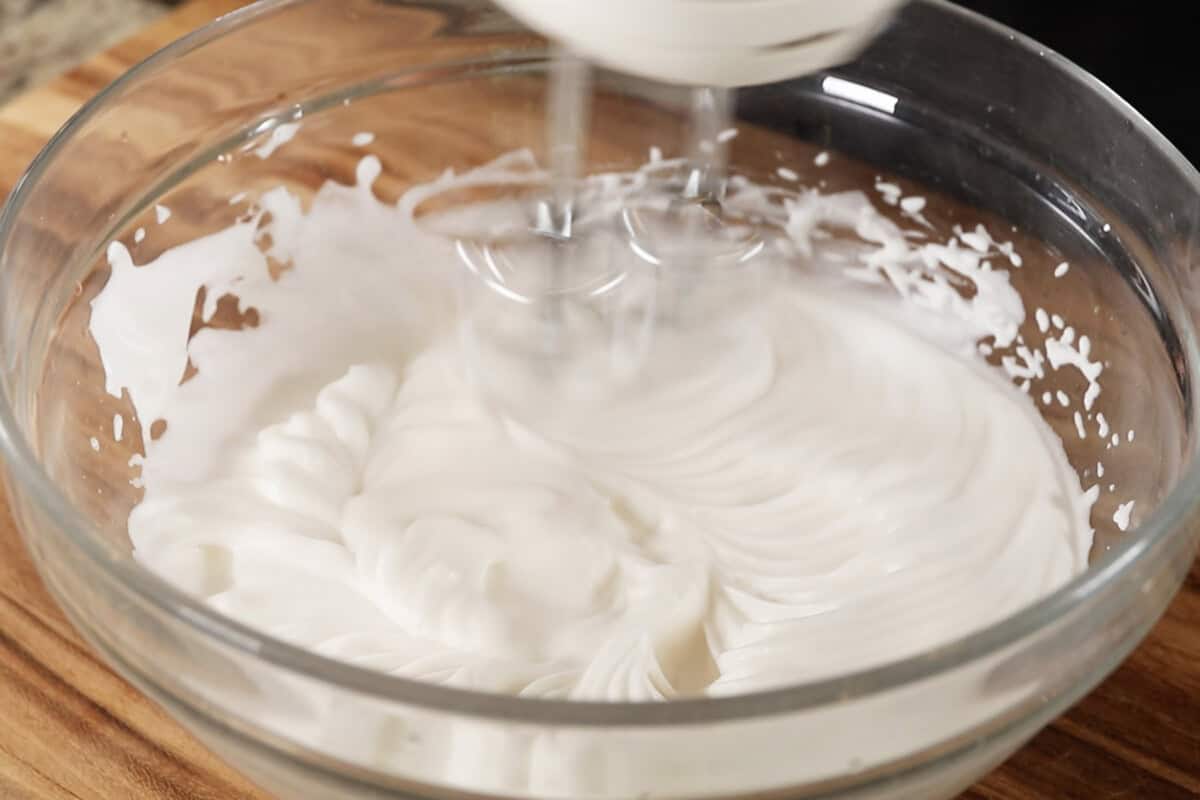 whipping vegan aquafaba meringue in large glass bowl