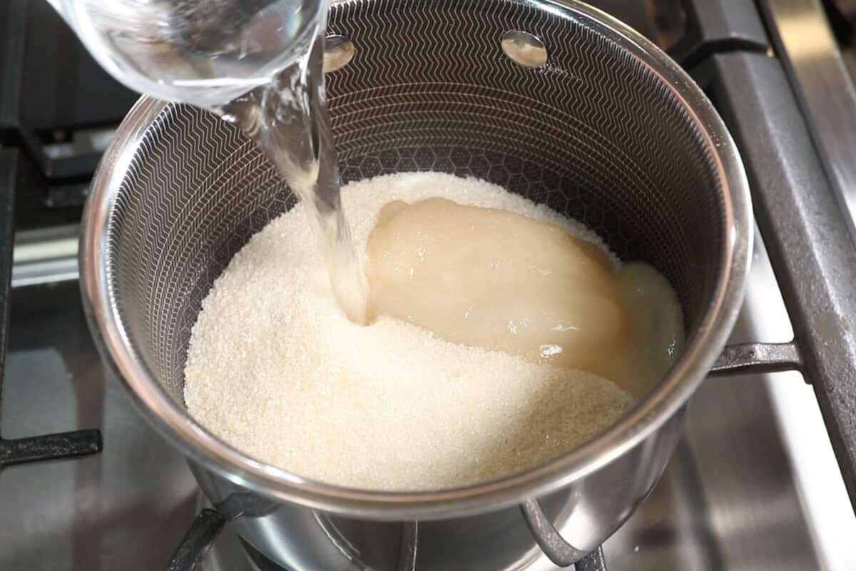 adding sugar and water to small pot