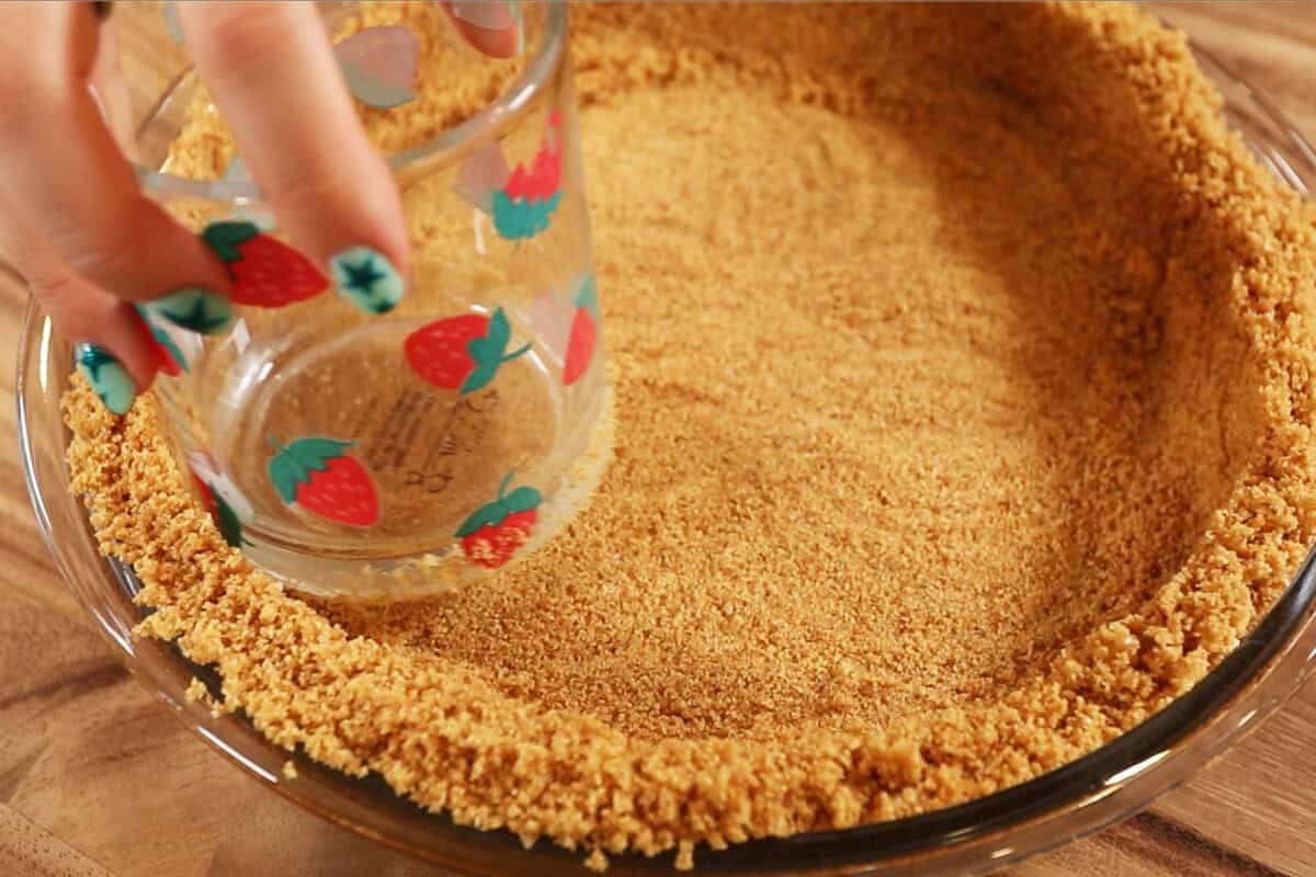 preparing a graham cracker crust for S'mores Pie