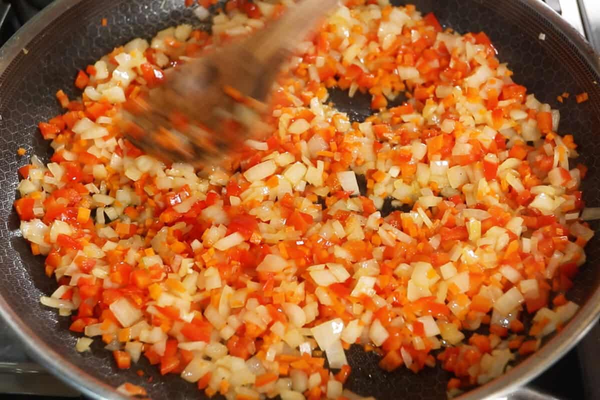 cooking onions, garlic, and carrots in a pan