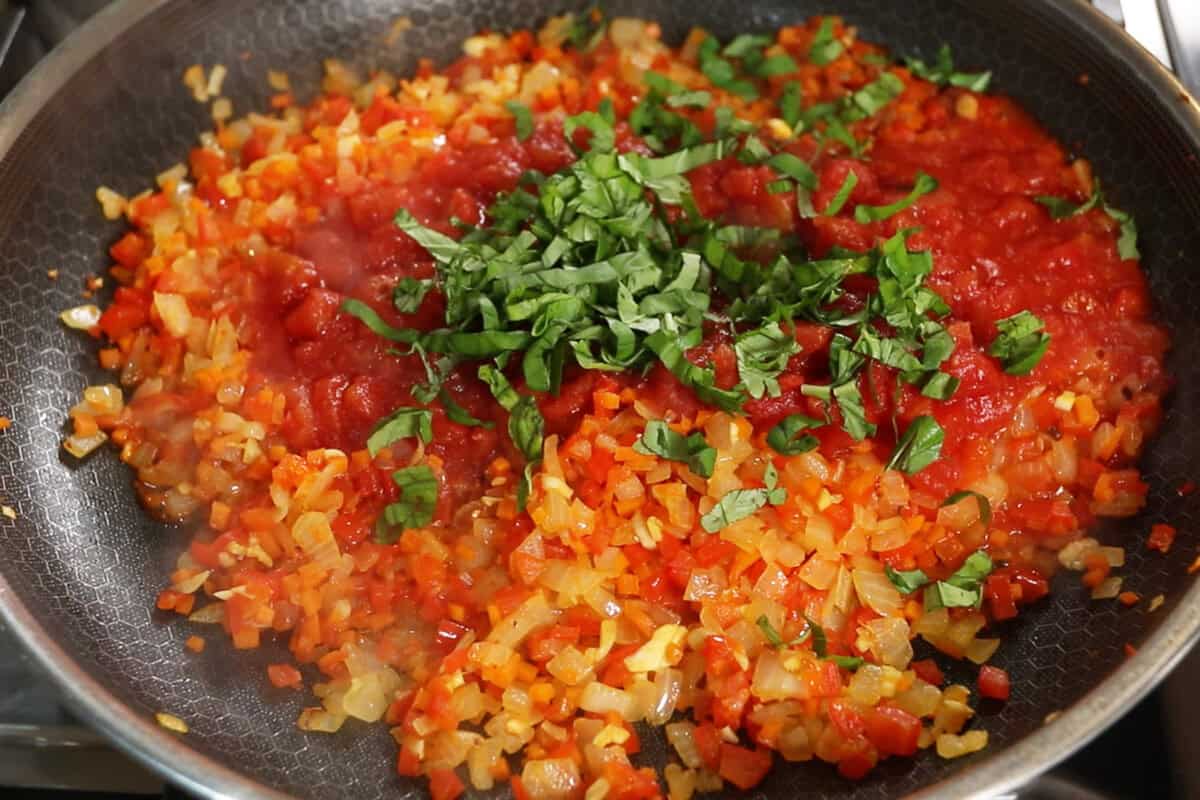 adding fresh basil to sauce