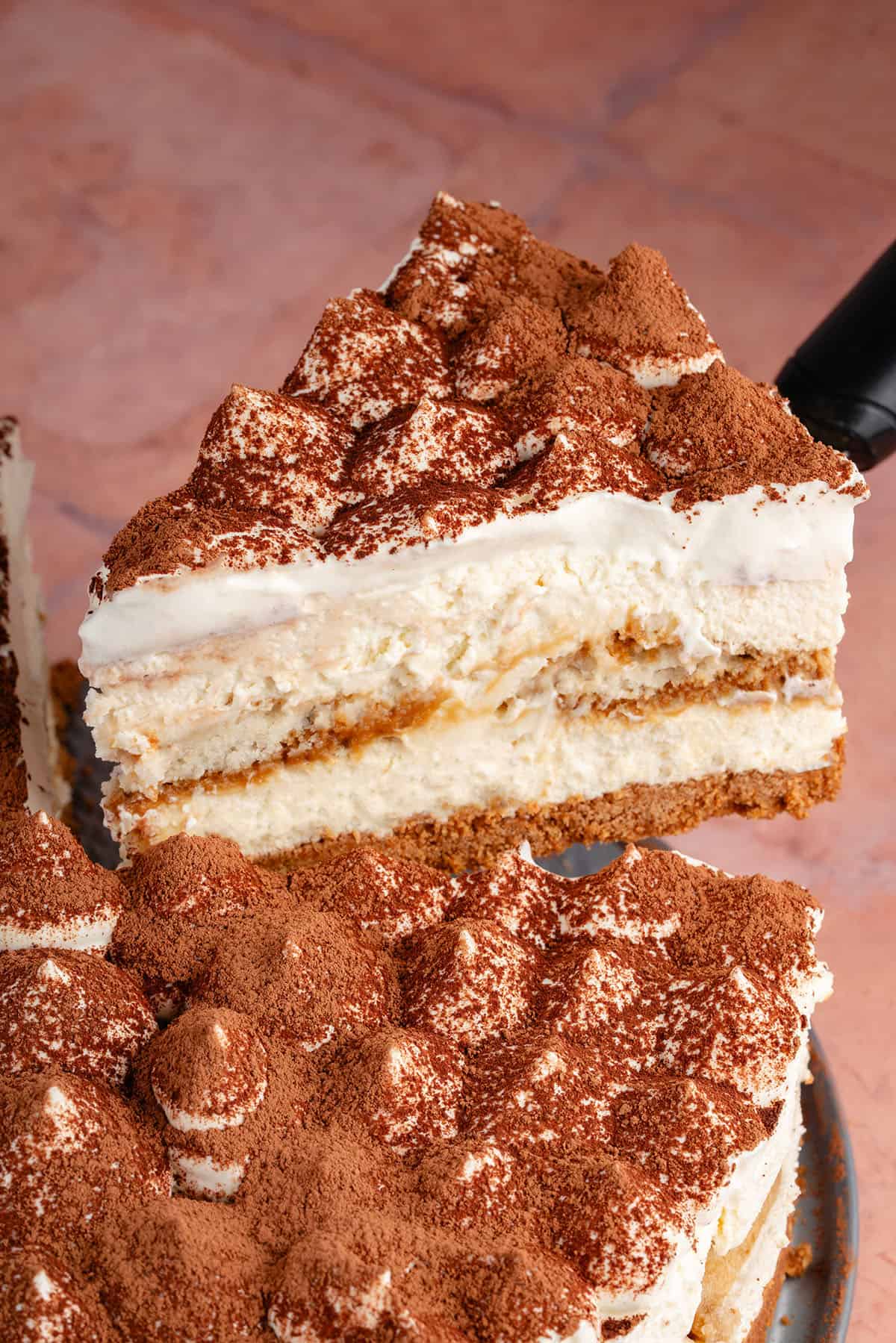 lifting a slice of tiramisu cheesecake up with spatula