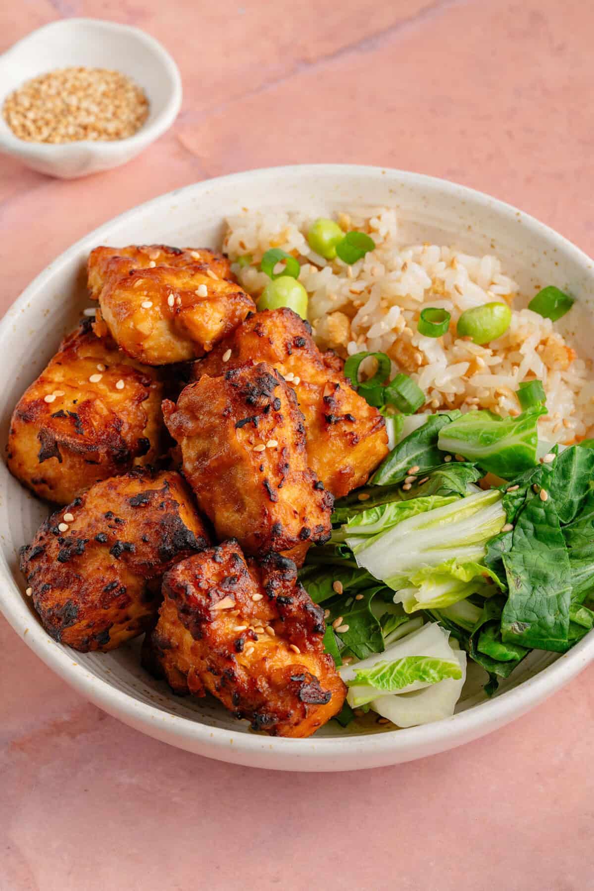 bowl of air fried miso sesame tofu with fried rice and greens