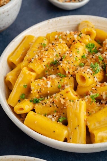bowl of creamy vegan butternut squash mac and cheese topped with everything bagel panko bread crumbs and parsley