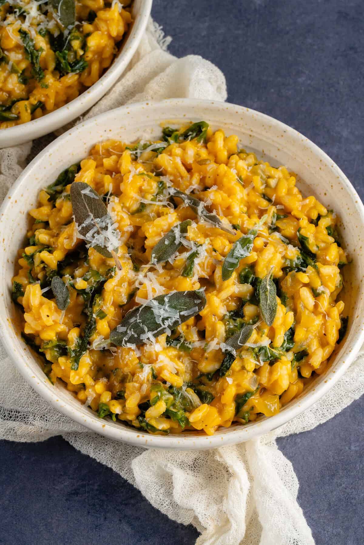 Bowl of butternut squash risotto with kale topped with fried sage and vegan parmesan