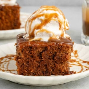 slice of chai sticky toffee pudding topped with ice cream and drizzled with caramel on a white plate