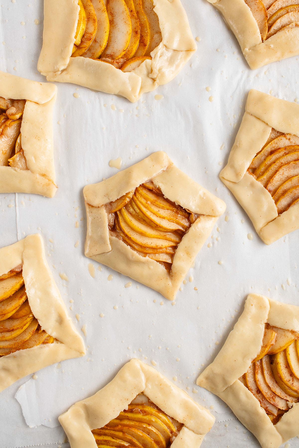 unbaked Mini Spiced Pear Galettes on parchment paper