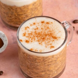two glasses of pumpkin chai latte overnight oats on a pink background