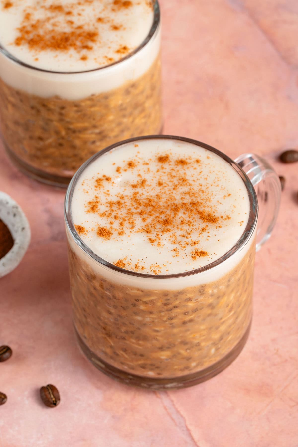 two glasses of pumpkin chai latte overnight oats on a pink background