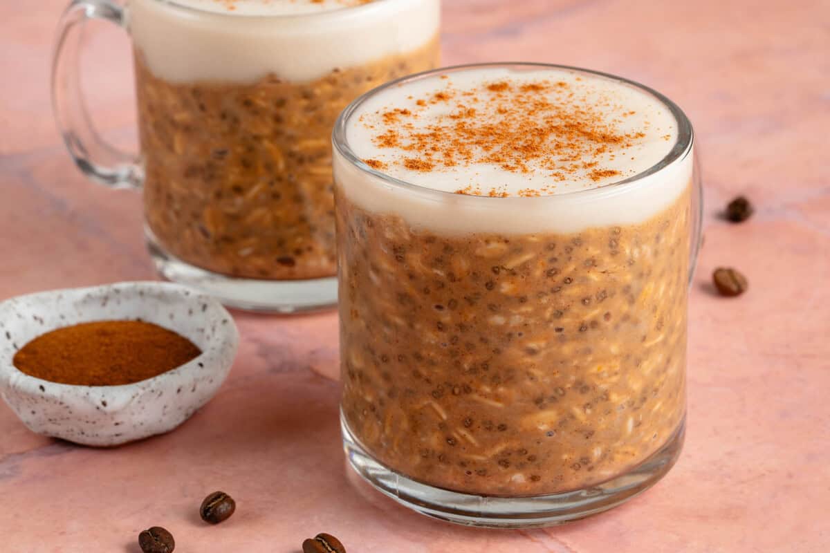 glass of pumpkin chai latte overnight oats on pink background