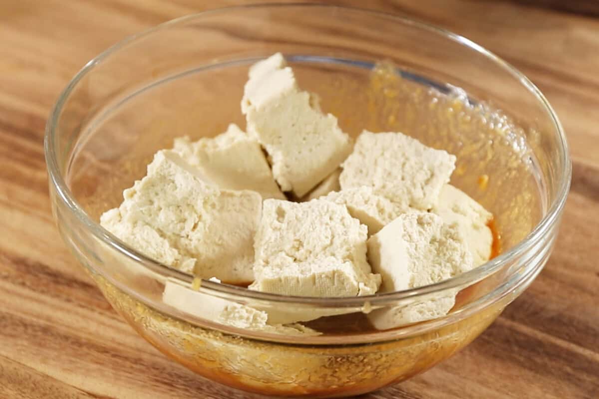 tofu chucked added to bowl of sauce