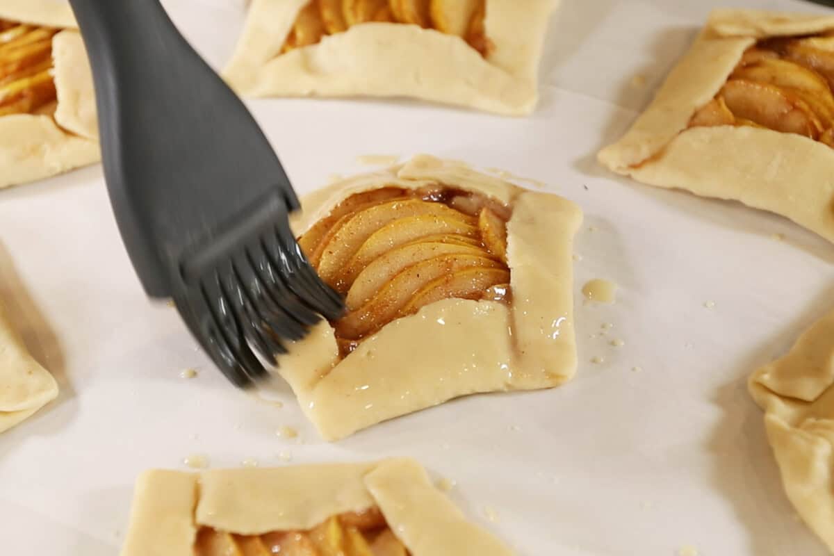 brushing pie crusts for Mini Spiced Pear Galettes