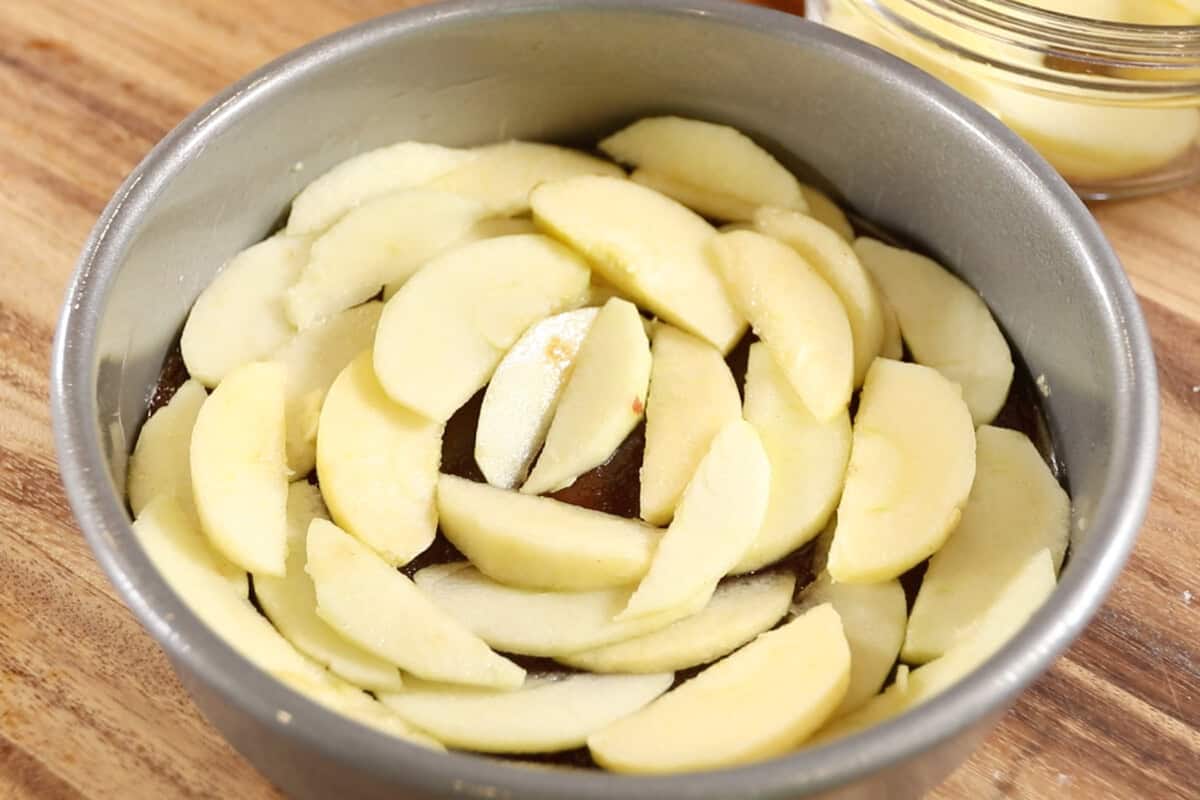 apples arranged over the caramel in cake pan