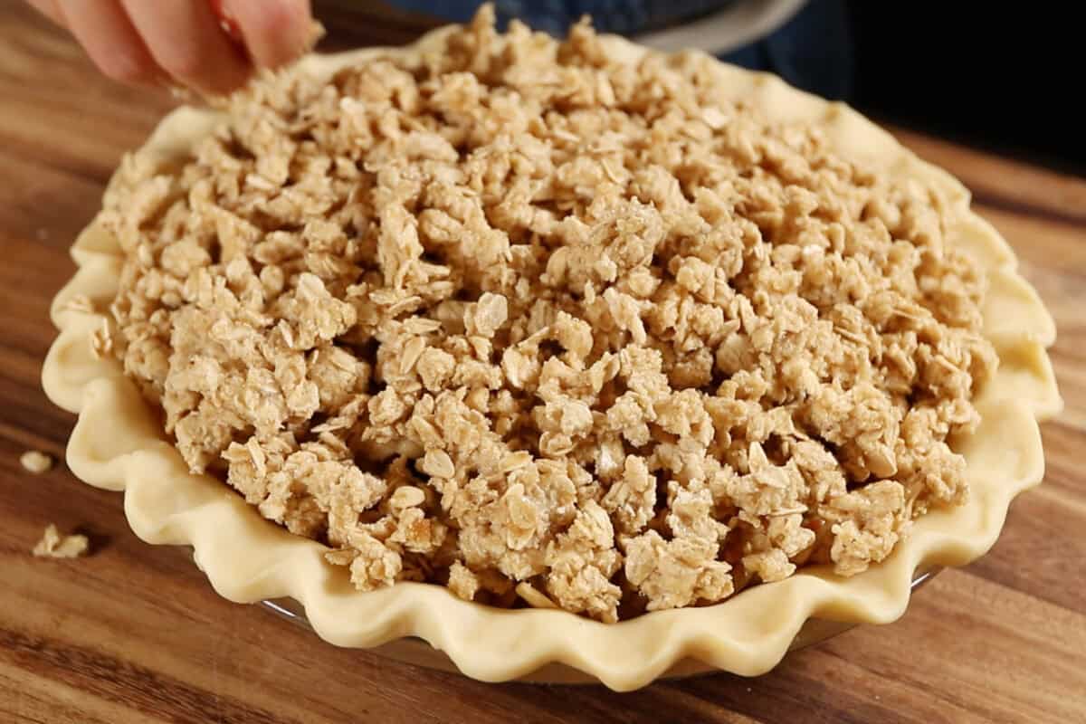 adding the crumble topping to the pie