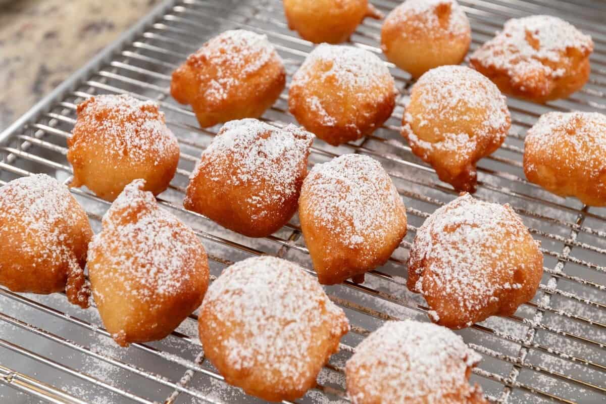finished zeppole dusted with powdered sugar on a cooling rack