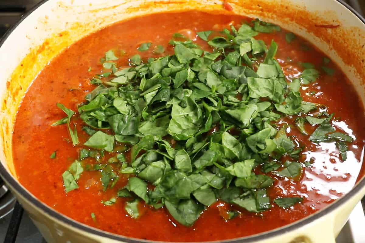 adding spinach to pot of soup