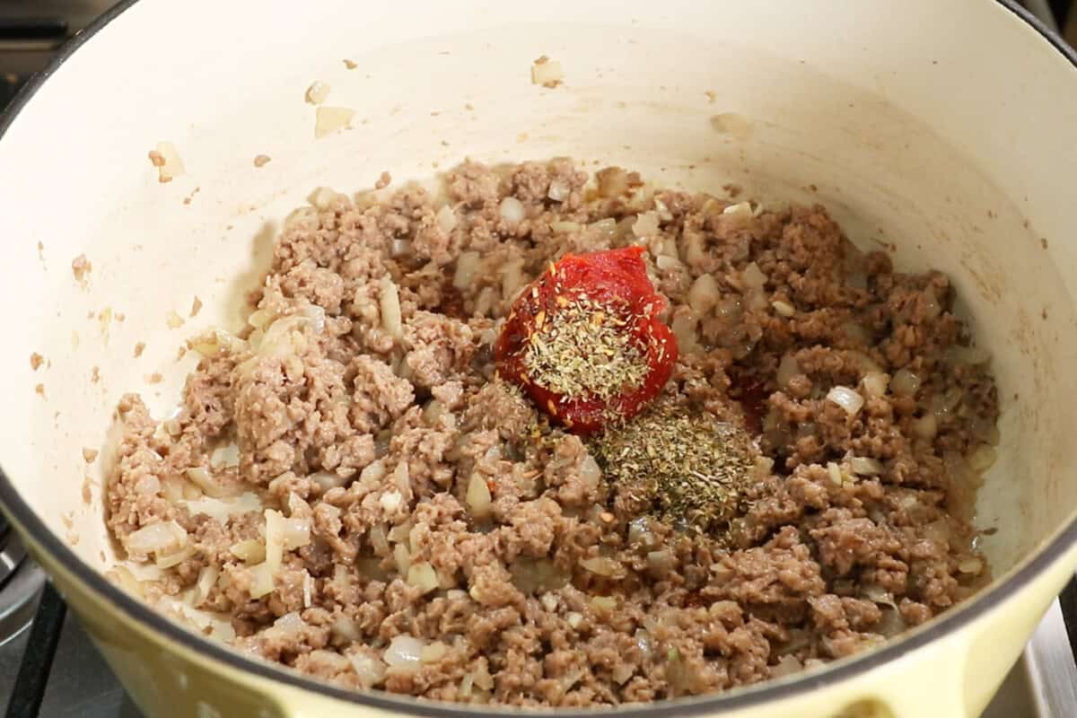 adding seasoning and tomato paste to cooked vegan beef