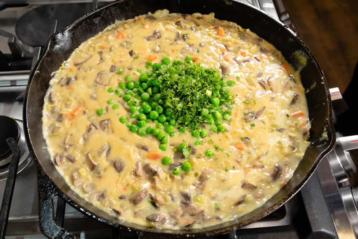 creamy dairy free mushroom pot pie filling with peas and parsley in large skillet