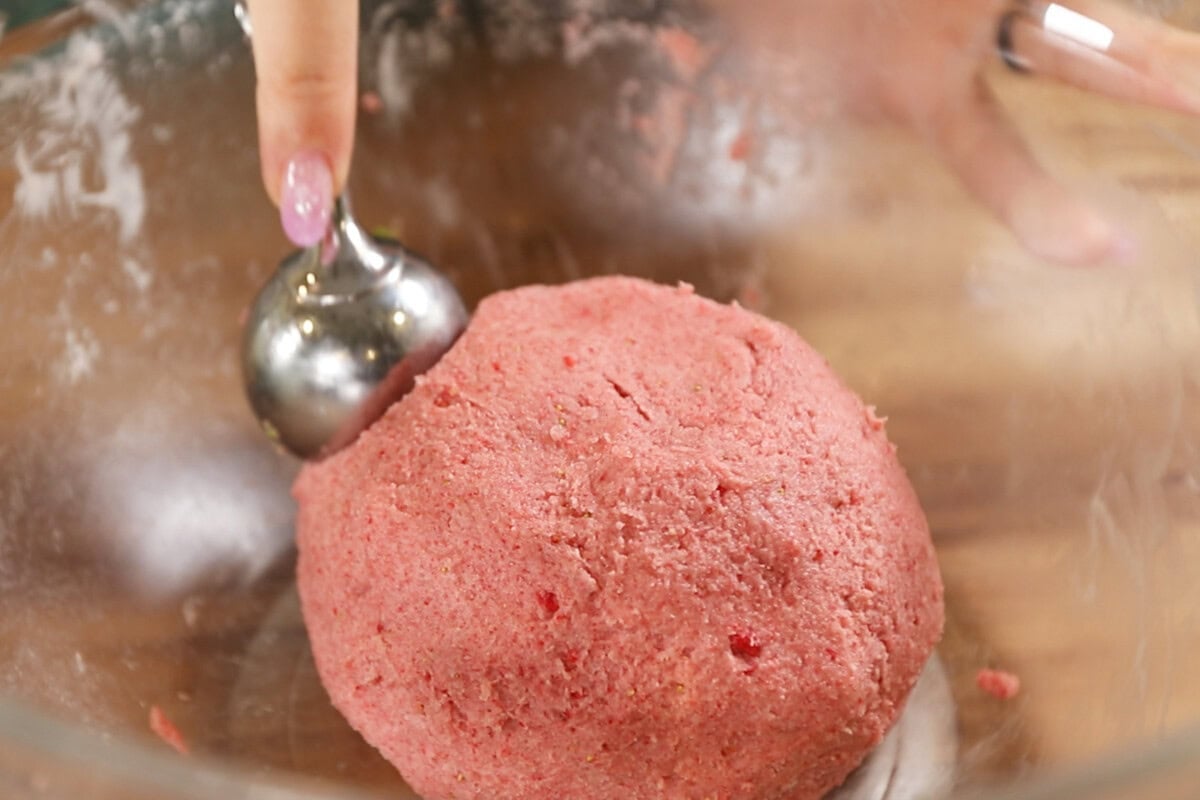 scooping strawberry sugar cookie dough from glass bowl