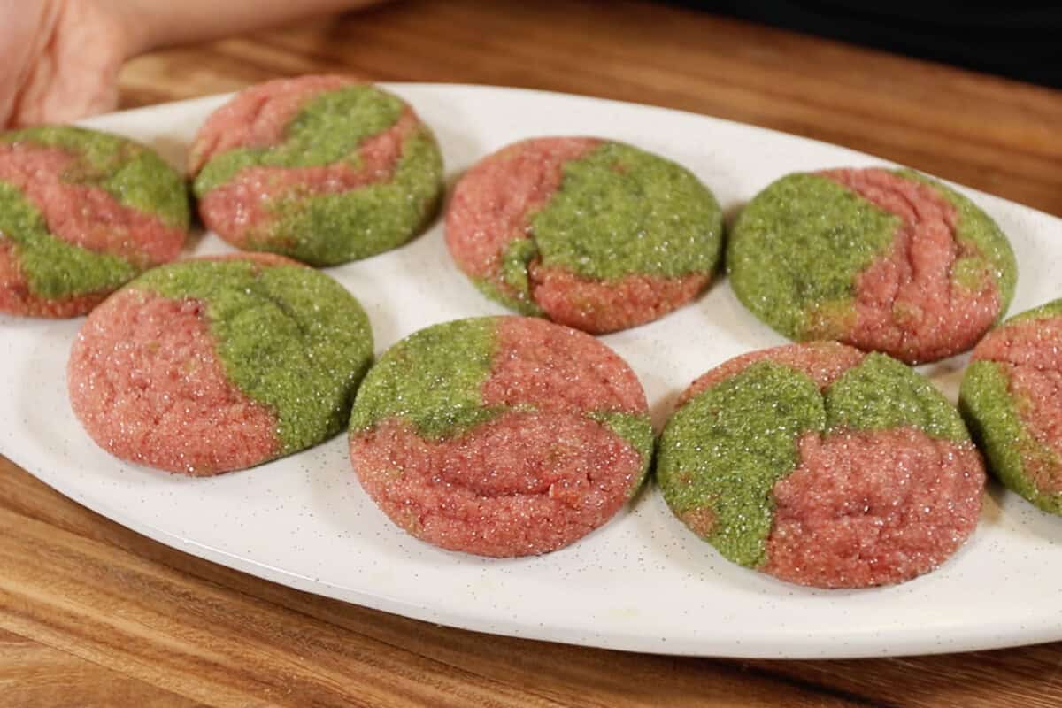 horizontal photo of marbled pink and green cookies on a white tray