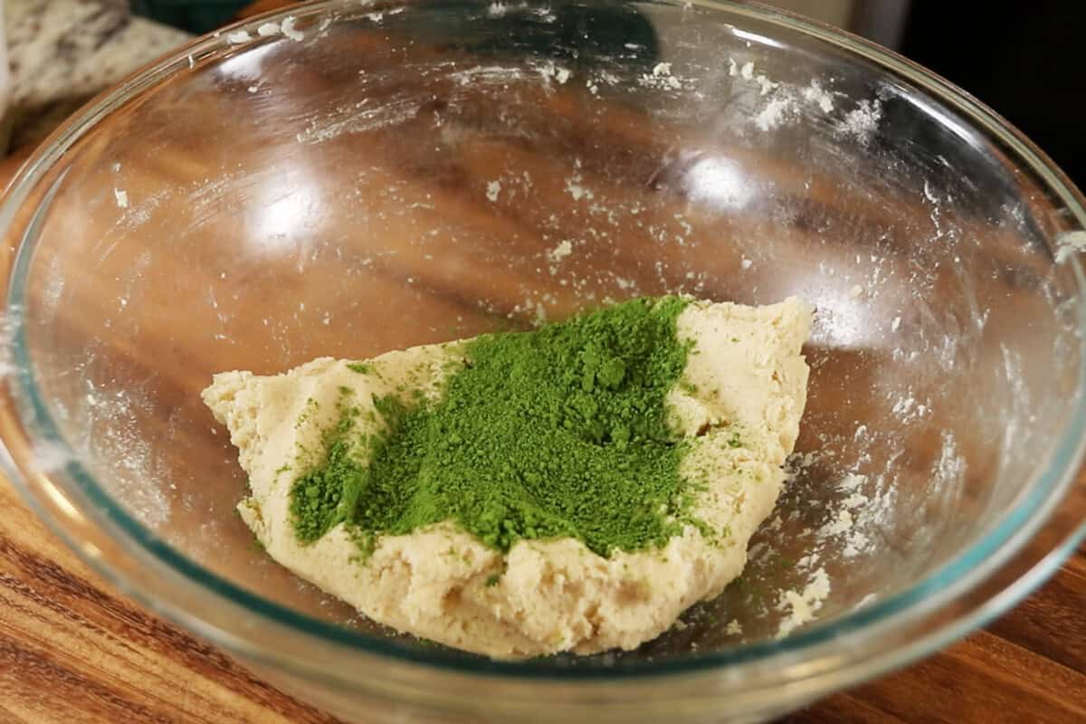 glass bowl of matcha powder on sugar cookie dough