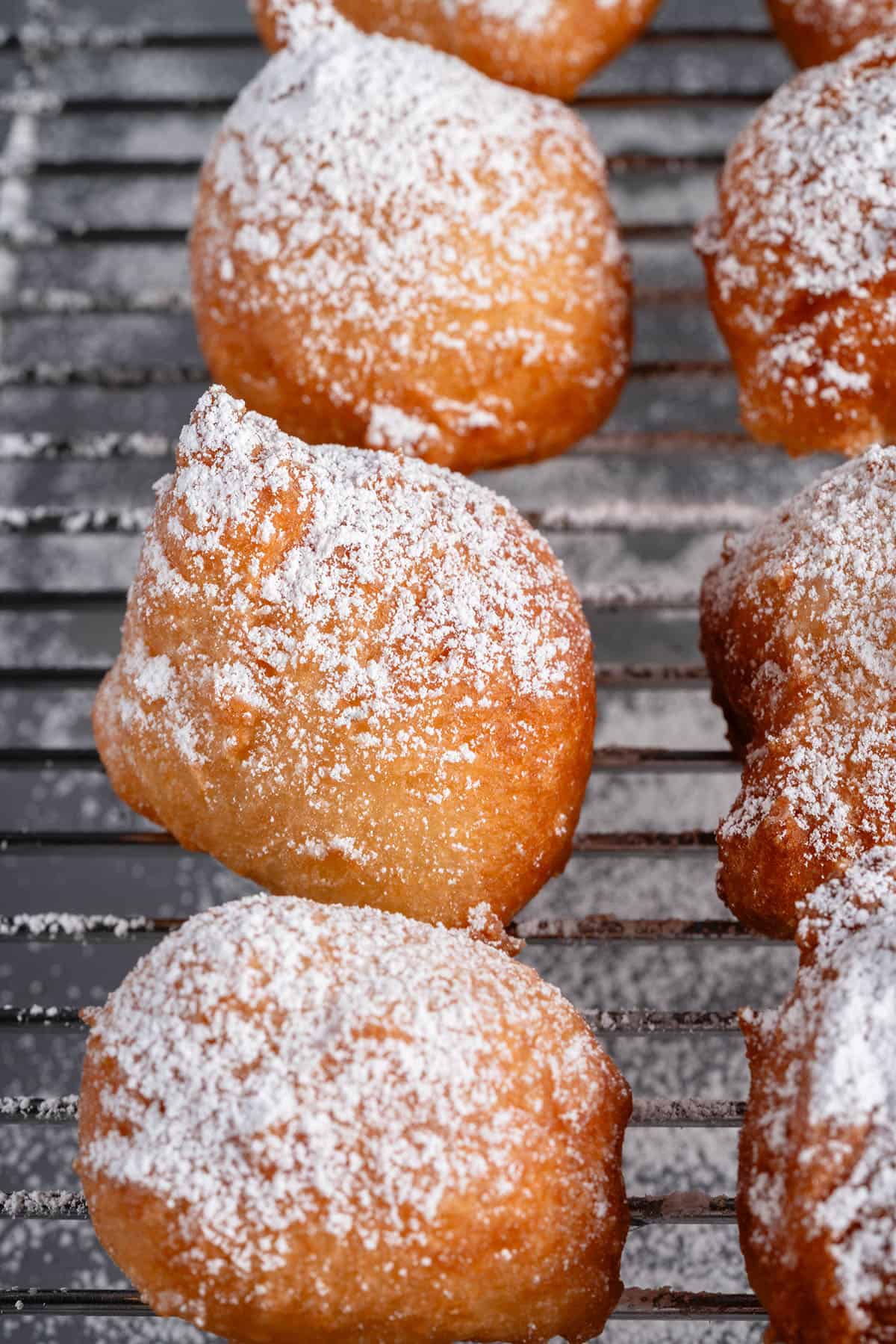 vegan zeppole dusted with powdered sugar on cooling rack